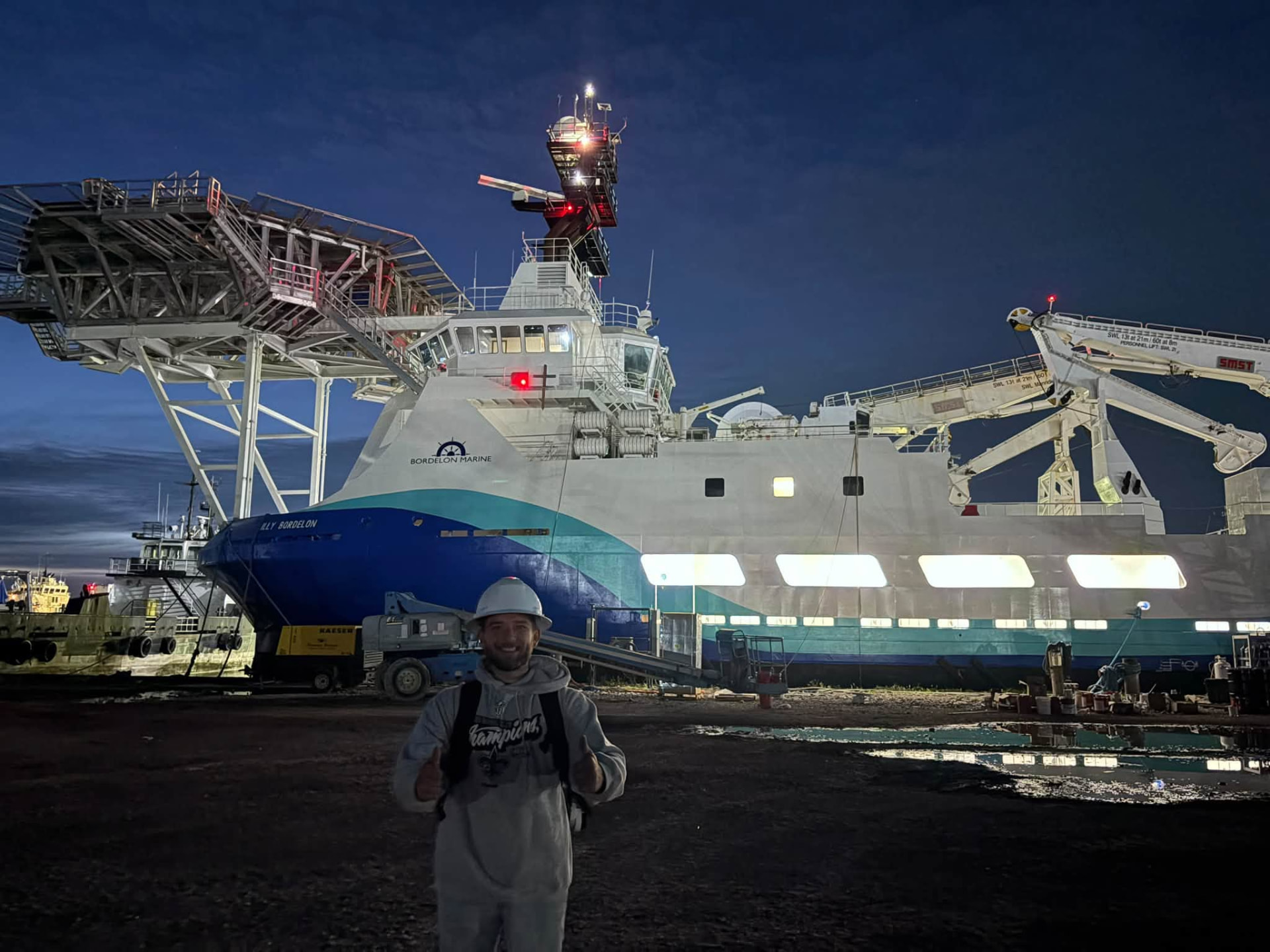 Offshore supply vessel lit up at night during shipyard electrical work