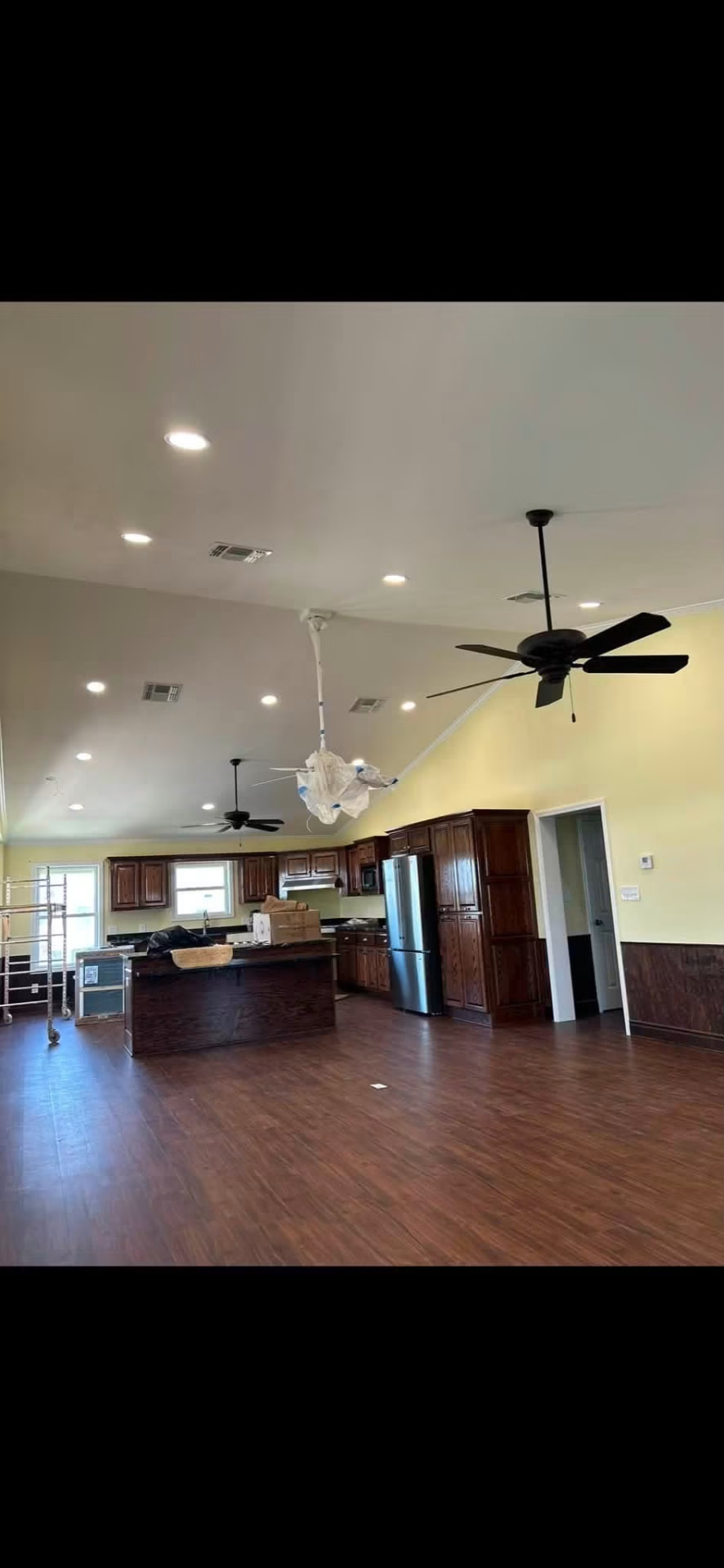 Open living and kitchen area with recessed lighting and ceiling fans